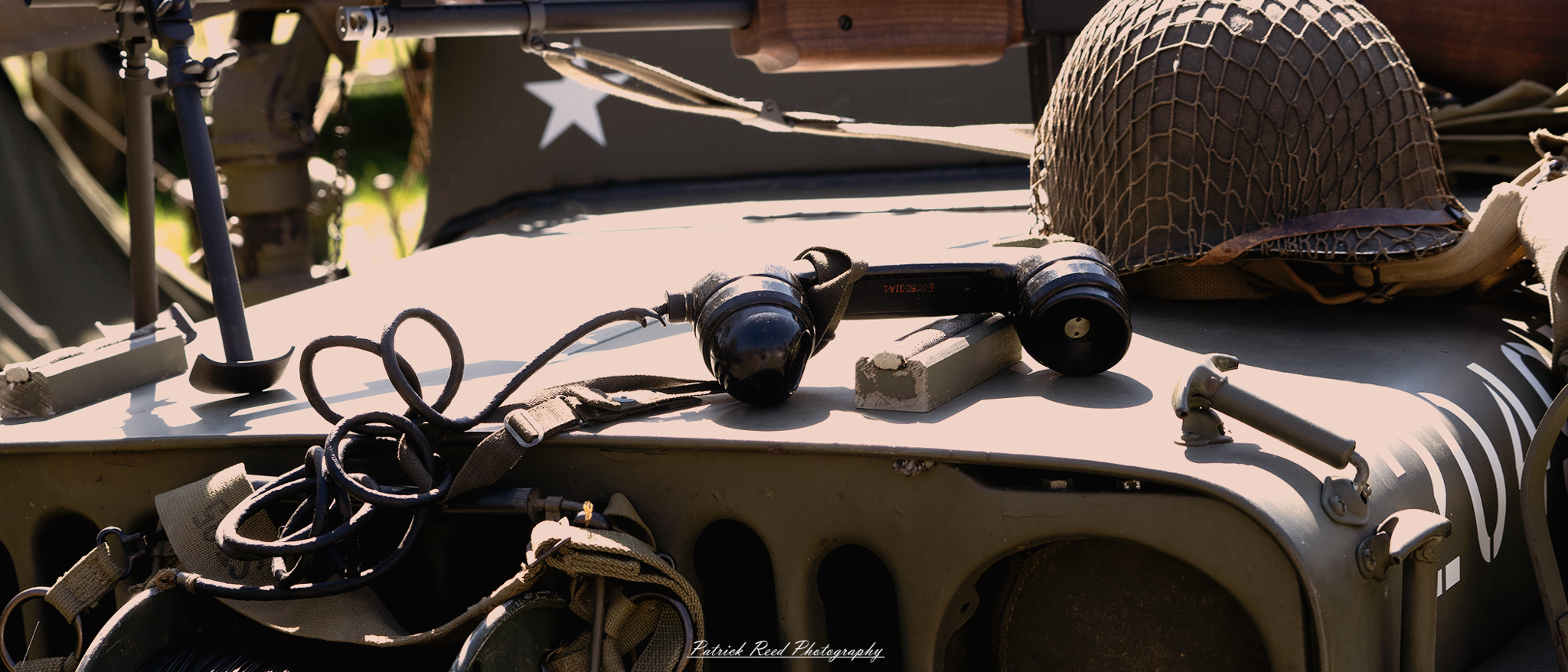 "An old rotary telephone resting on the hood of a World War II-era jeep, showcasing a unique blend of history. The jeep, with its military green paint and rugged design, serves as a backdrop to the vintage phone, highlighting the contrast between modern communication and wartime machinery. Sunlight glints off the jeep's metal surface, casting shadows that evoke a sense of nostalgia. This image captures a moment in time, reflecting the daily life and challenges faced by soldiers during the war."